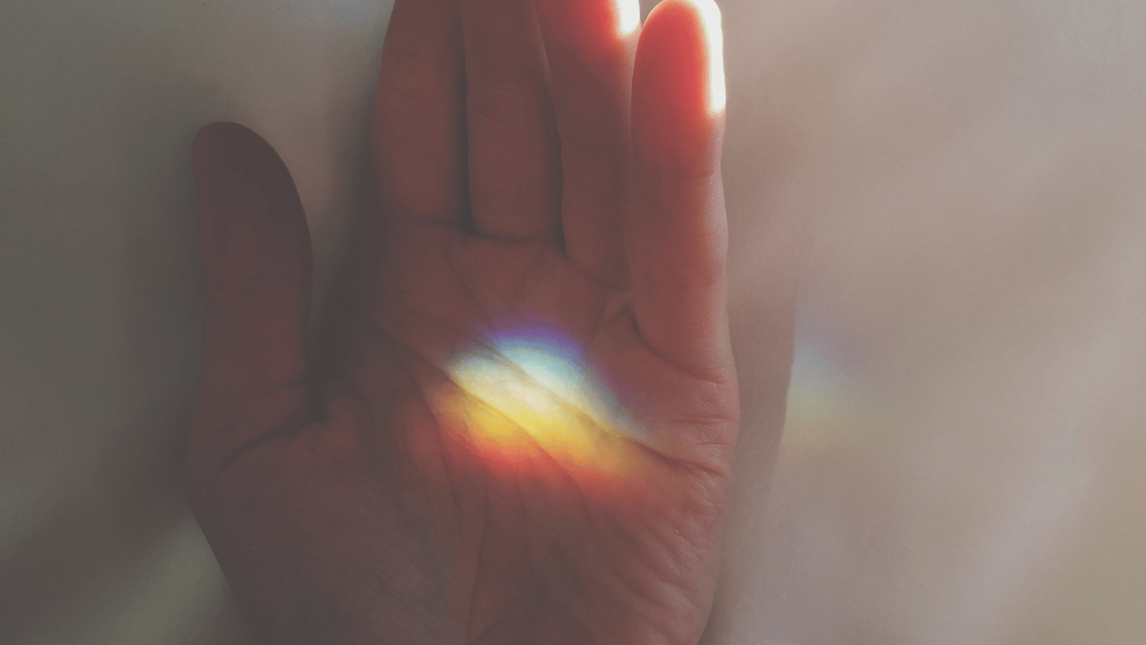 Mano iluminada por un rayo de luz simbolizando energía y conciencia.